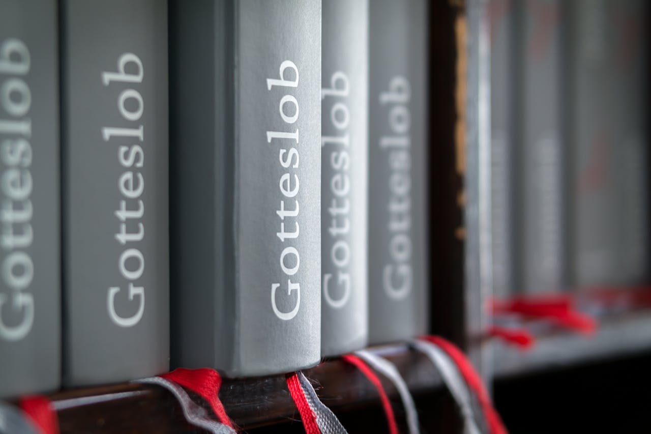 Macro shot of Gotteslob hymn books with red bookmarks neatly arranged on a bookshelf.